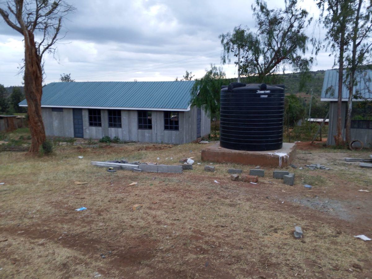 Completed building with green corrugated roof and water storage tank