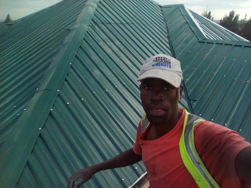 Madao roofing crew member on a finished green corrugated roof