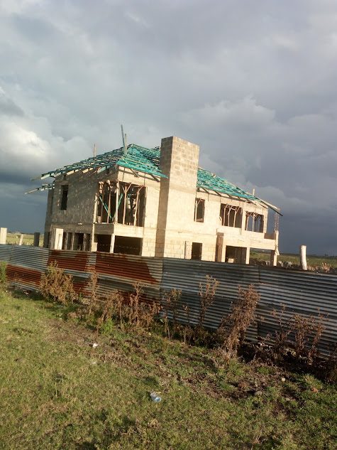 Stone house with chimney and roof trusses under a stormy sky