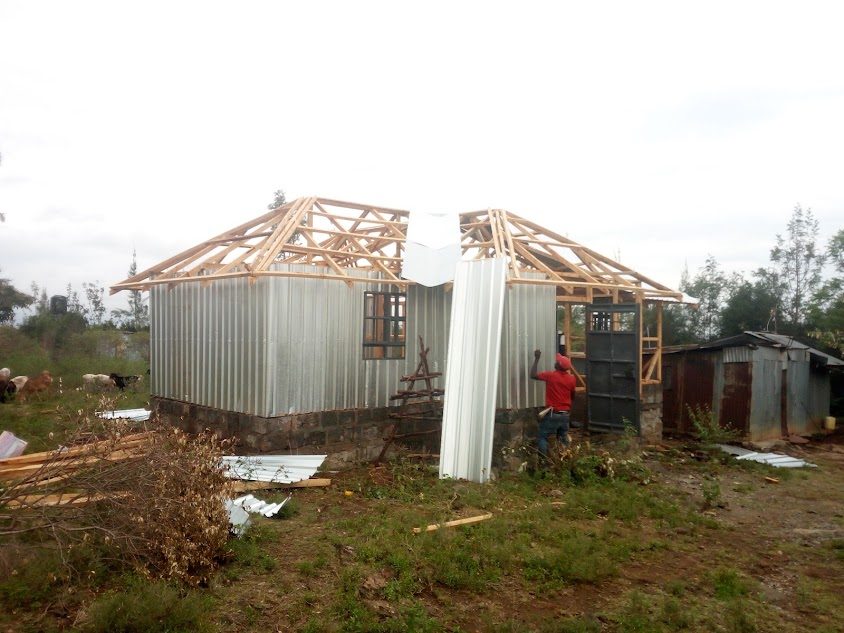 Timber-framed structure with sheet metal roofing and siding being installed